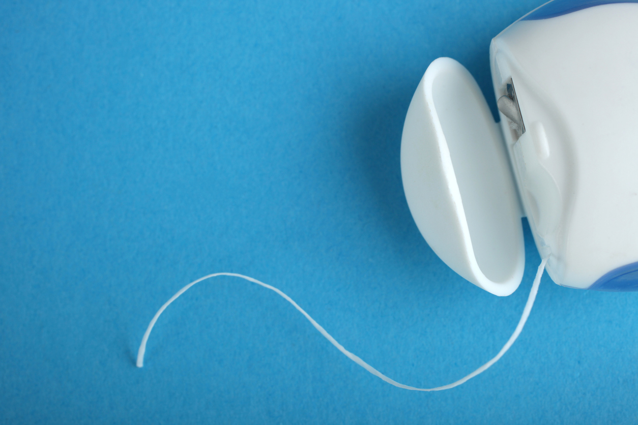 Dental floss on a blue background. Copy space.